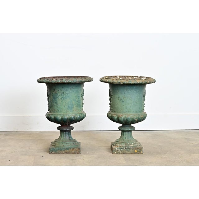 An elegant pair of late 19th century French cast iron planters in the silhouette of Medici urns", displaying a...