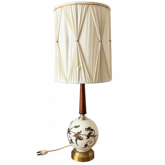A distinctive vintage table lamp featuring a glossy ivory globe adorned with raised botanical vines, curling tendrils, and...