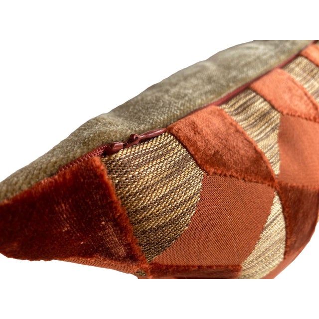 This pillow features a bold, geometric pattern in rich terracotta and earthy taupe tones, with a three-dimensional effect...