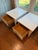 An elegant matching pair of Brandt nightstands featuring a white painted finish, decorative gold-tone drawer pulls, and...
