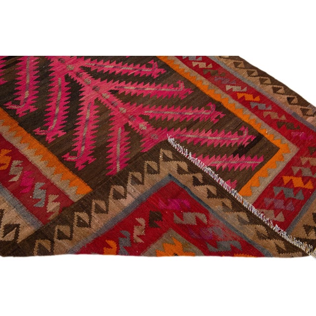 Beautiful vintage Turkish Kilim hand-knotted wool rug with a pink field. This piece has a red frame and multicolor accents...