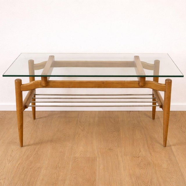 Mid-Century Modern style coffee table from the 1950s with a restored beech wood structure and glass top. Features a lower...