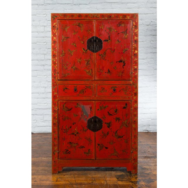 A Chinese Qing Dynasty period red lacquered cabinet from the 19th century with four doors, two drawers and hand-painted...
