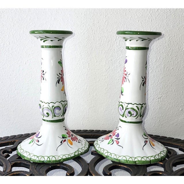 A pair of ceramic, polychrome, taper candle holders. Featuring a delicate handpainted floral pattern on white with a...