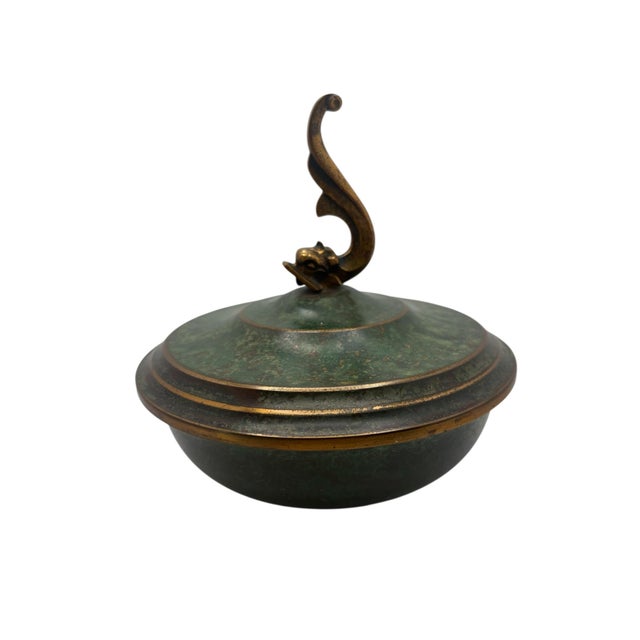A vintage Arts & Crafts style bronze covered dish with a dolphin finial lid by Carl Sorensen, ca. 1920’s. The dish has the...