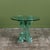 .Postmodern occasional table is anchored by a heavy, geometric pedestal base composed of interlocking, solid cast-glass...