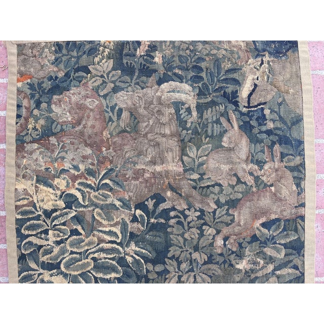 An early 17th-century tapestry depicting a leopard, rabbits, and a goat within a lush verdure landscape. Dimensions: 39 x...