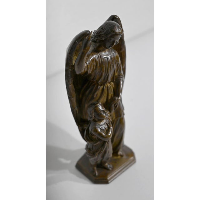 Small patinated bronze with ocher reflections, representing a winged angel with long hair, dressed in a tight drape at the...