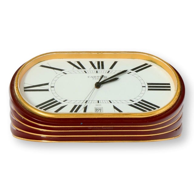 Vintage Cartier Paris oval accordion desk clock with burgundy and gold enamel body, Roman numerals, and date window. Swiss...