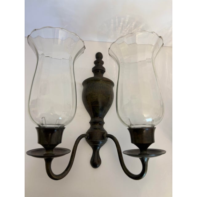This vintage wall sconce with hurricane glass shades is a modern reporoduction by the Gatco Company which is recognizable...