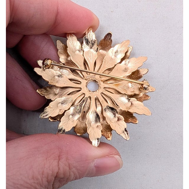 1960s goldtone white rhinestone cabochon center with textured leaves surrounding it, flower brooch with security clasp....
