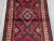 This vintage Afghan hand-knotted wool runner rug features a bold tribal geometric pattern woven in deep tones of red,...