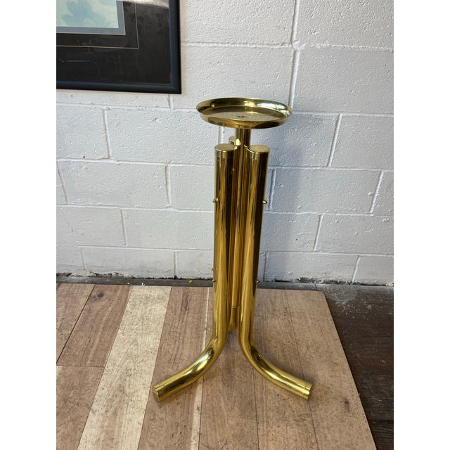 A striking Postmodern plant stand or display pedestal crafted in polished brass, featuring an architectural arrangement of...