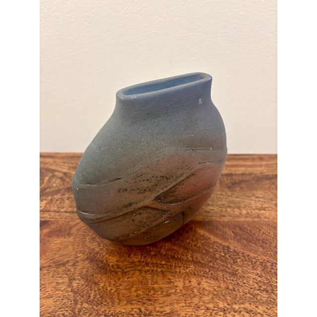 A sculptural vintage studio pottery vase handmade in Brazil. Its flattened organic form features a rough, tactile surface...