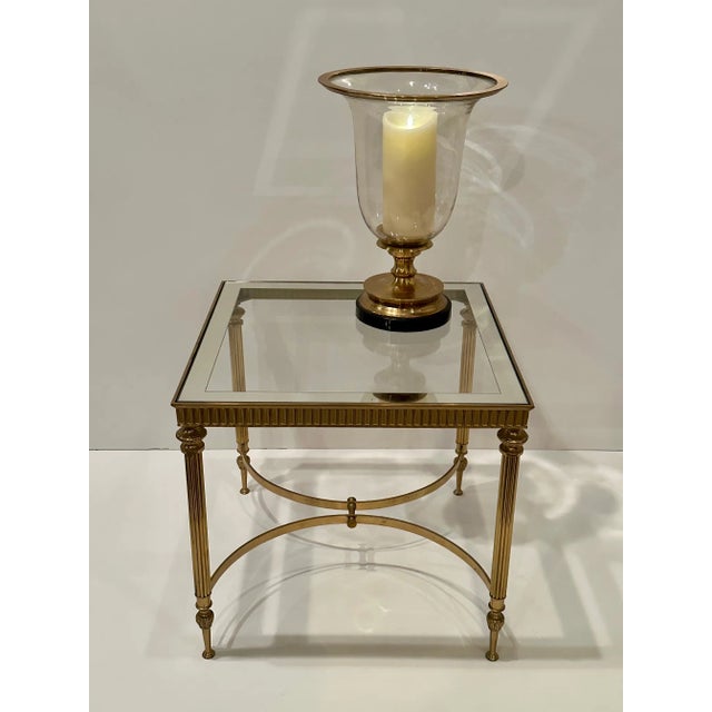 Classically elegant Maison Jansen French end table having brass base and glass top outlined with a silver band.