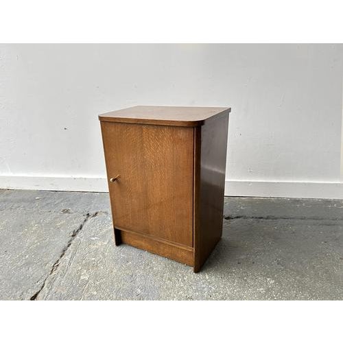 A compact cabinet ideal for the bedside features a rich glossy brown oak finish showing the wood grain. It has a single...