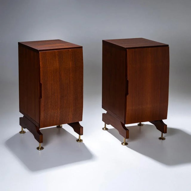 A pair of rectangular nightstands with a slightly convex door and conical brass legs. The nightstands have an interior...