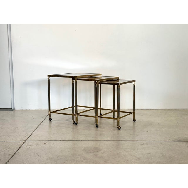 Set of three 1960s bar trolleys, brass frame and smoked glass tops, the size refers to the largest table.