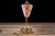 Mid-century American table lamp featuring a tapered ribbed pink glass body decorated with gilt motifs and supported by an...