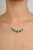 This elegant 18K yellow gold necklace features a modern bezel-set emerald, showcasing its vibrant green hue. The...