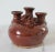 Vintage brown studio art pottery 3- stem bud vase with floral motif. Stamped by artist near base. Minor wear. No chips.