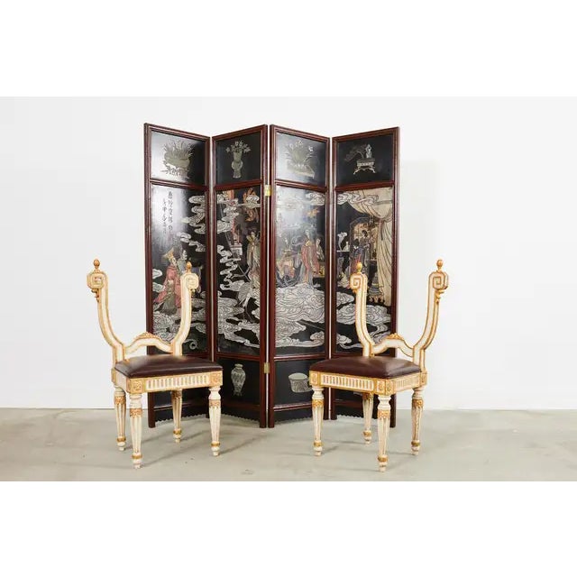 Opulent pair of Italian hall chairs made in the neoclassical style. The chairs feature a backless design having decorative...