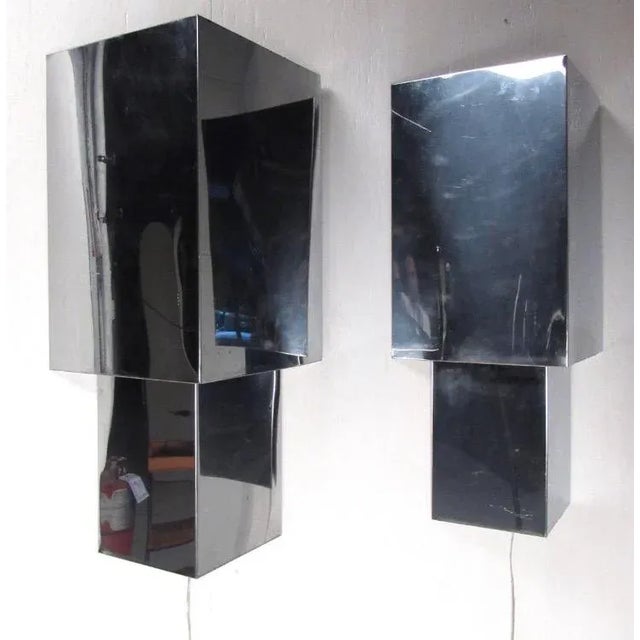 This matching pair of vintage chrome wall sconces features triangular metal construction, with unique wall-mounted design....