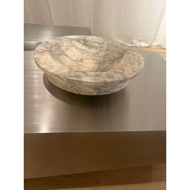 The Curvo Bowl by Michael Verheyden in Travertino Antico is crafted from natural stone, showcasing richly veined patterns...