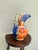 A boldly expressive hand-painted ceramic ewer with a rounded bulbous body, dramatically ruffled and fluted spout, and an...