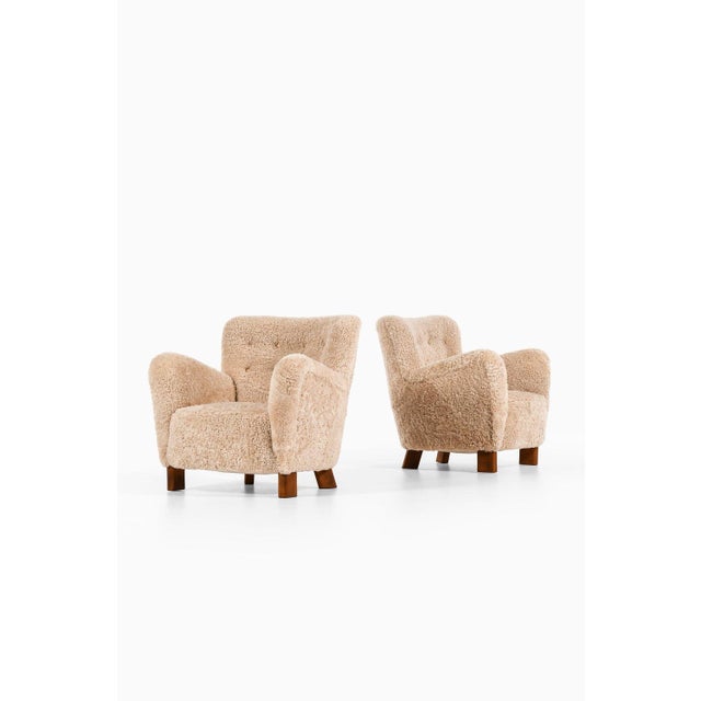 Pair of easy chairs in beech and newly reupholstered in sheepskin and natural leather buttons by fritz hansen, 1938...