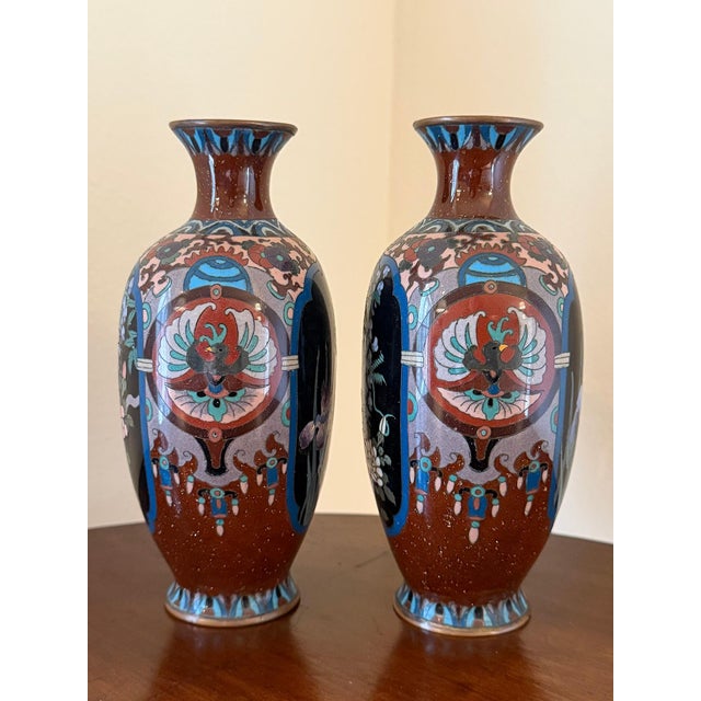 This is a pair of late 19th-century baluster Japanese cloisonné enamel vases, decorated in a deep burgundy red ground....
