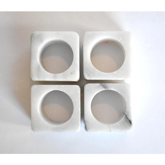 A set of 4 vintage white marble napkin rings with grey veins, square on the outside and round on the inside.