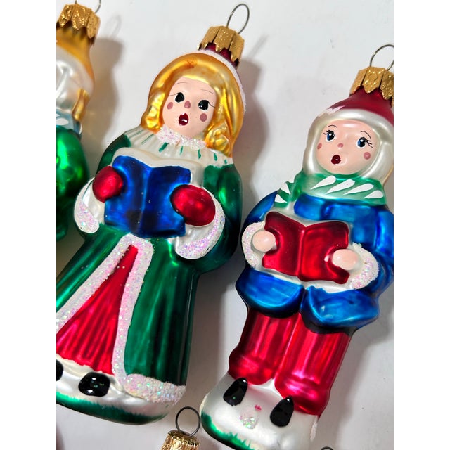 A collection of seven vintage glass Christmas ornaments featuring four red-suited Santas and three colorful Christmas...