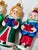 A collection of seven vintage glass Christmas ornaments featuring four red-suited Santas and three colorful Christmas...