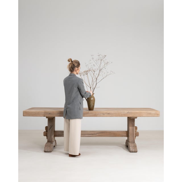 A generously scaled French oak trestle dining table, embodying rustic craftsmanship and enduring construction. The solid...