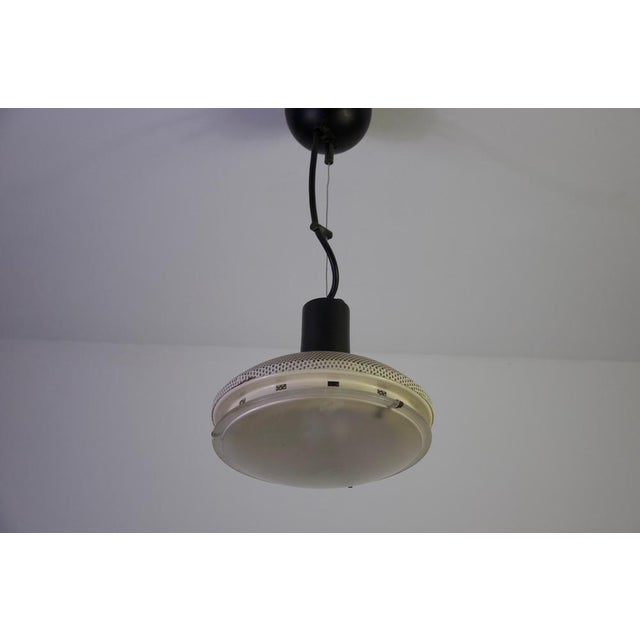 White italian ceiling lamp, 1970s. This distinctive vintage pendant light features a rounded white metal shade with a...