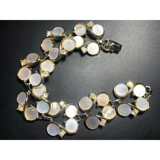 MCM Lisner mother-of-pearl bracelet feature natural disc-cut shell cabochons set within gold plated S-curve or wave links...