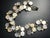 MCM Lisner mother-of-pearl bracelet feature natural disc-cut shell cabochons set within gold plated S-curve or wave links...