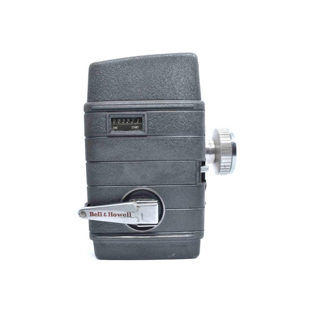 This mid-century Bell & Howell "Two Twenty" 8mm movie camera is a classic piece of 1950s Americana, featuring a rugged...