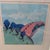 Framed pastel landscape by artist J. Russell. Soft blue sky with white clouds over rolling green hills, a cluster of blue...