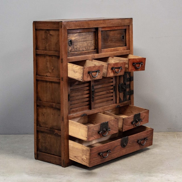 Antique Japanese merchant chest (Choba Tansu) featuring nine drawers and a pair of small sliding doors, accented with hand...