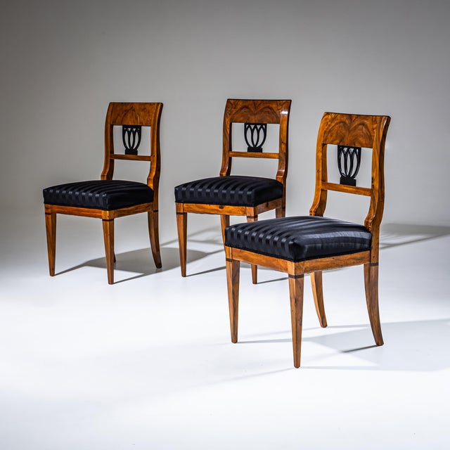 Set of three Biedermeier chairs crafted from walnut. The backrests feature ebonized pierced decoration in the form of...
