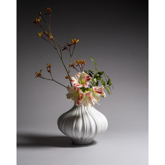 Large Plissé vase in matte white porcelain with deep flowing pleats that catch light with quiet precision. The folded...