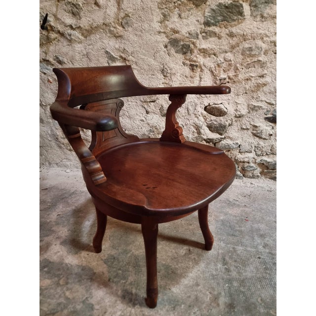 This antique desk chair dates from the early 20th century and is crafted from solid walnut. It features a continuous...