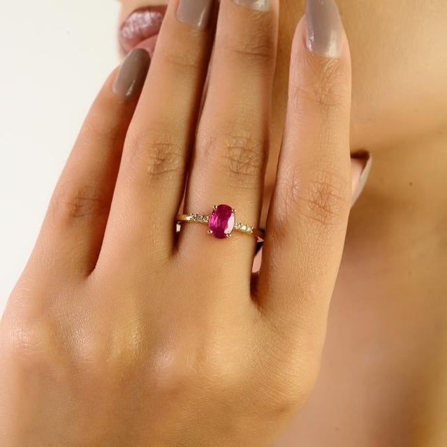 This minimal oval-cut ruby solitaire ring, crafted in 14K solid yellow gold. The centerpiece features a vivid oval ruby of...