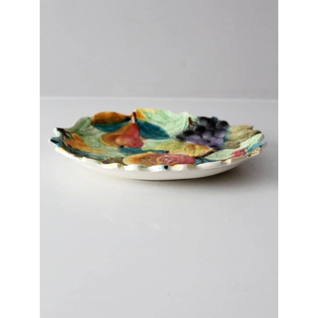 A vibrant Italian majolica plate featuring raised fruit and leaf motifs along a softly scalloped edge. Hand-painted in...