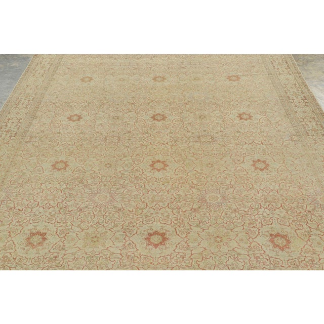 Handwoven in wool, circa 1920–1930, this antique 7x10 Tabriz rug features an intricate all-over floral design in muted...