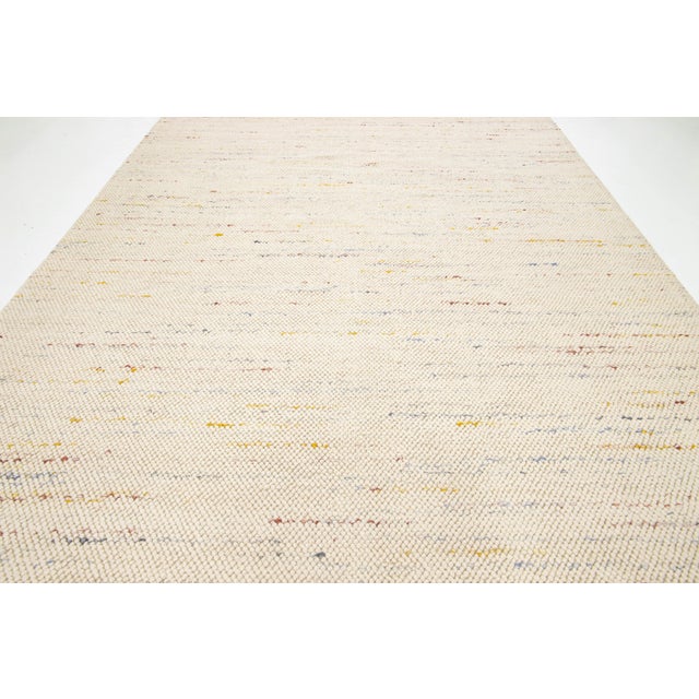 This modern textured Indian hand-knotted wool rug is skillfully woven by artisans and features a multicolored soft design....