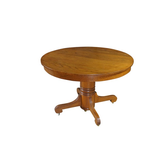 This antique round oak pedestal dining table showcases classic late 19th to American craftsmanship, built with a versatile...