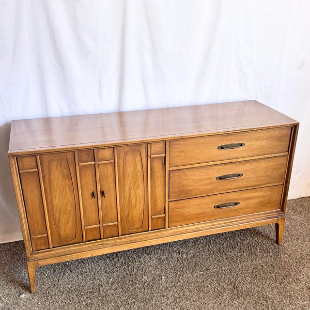 This refined Mid Century Modern walnut credenza showcases clean architectural lines and a warm, honey-toned wood finish...